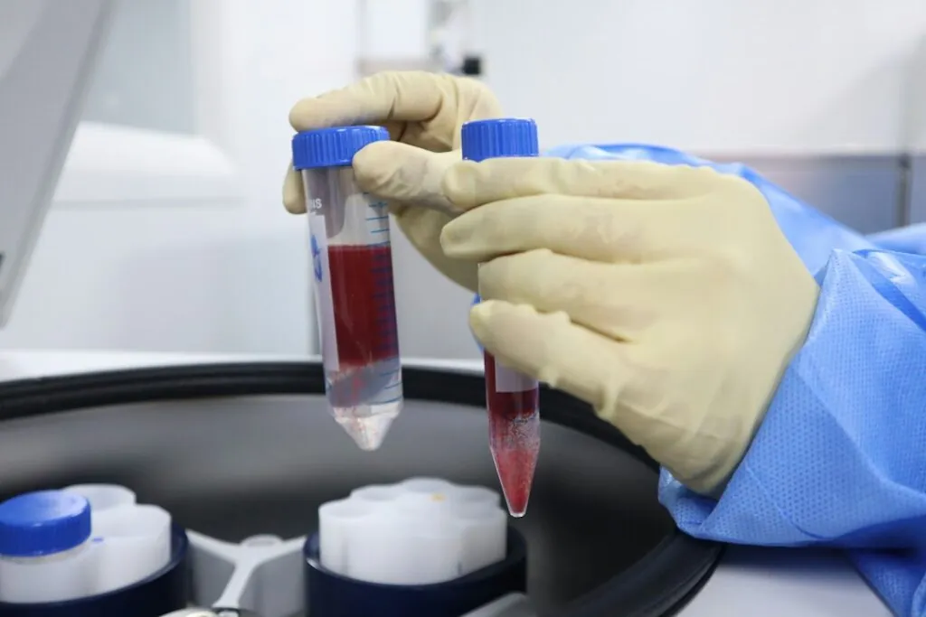 Gloved hand placing blood sample tubes into a centrifuge