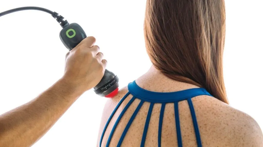 Clinician applying a handheld laser therapy device to a patient's shoulder