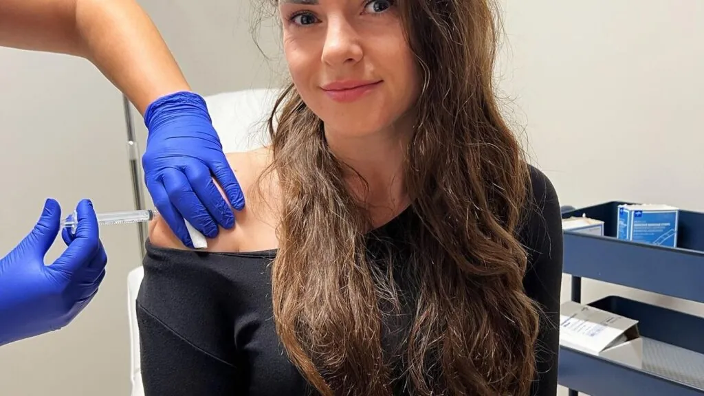 Gloved clinician giving a patient an injection in the shoulder