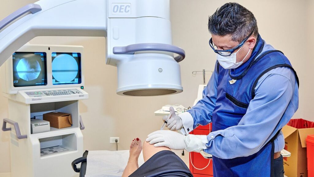Medical professional performs injection procedure using fluoroscopy imaging.