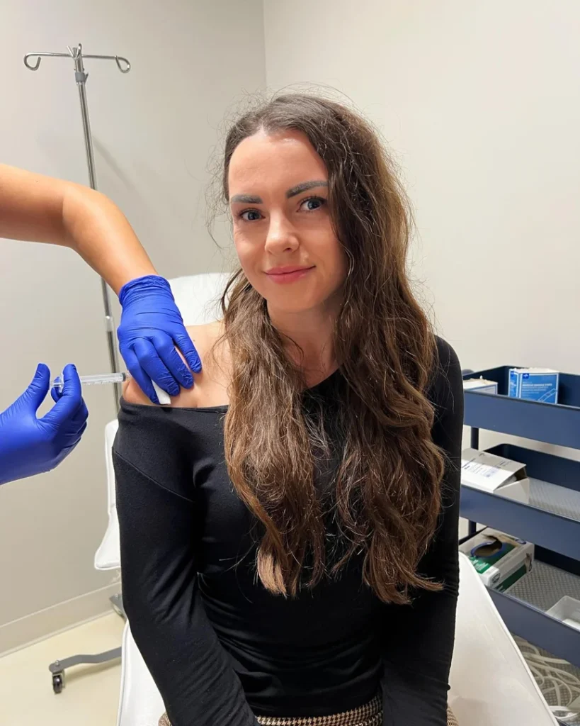 Smiling patient receiving an injection in the shoulder in an exam room